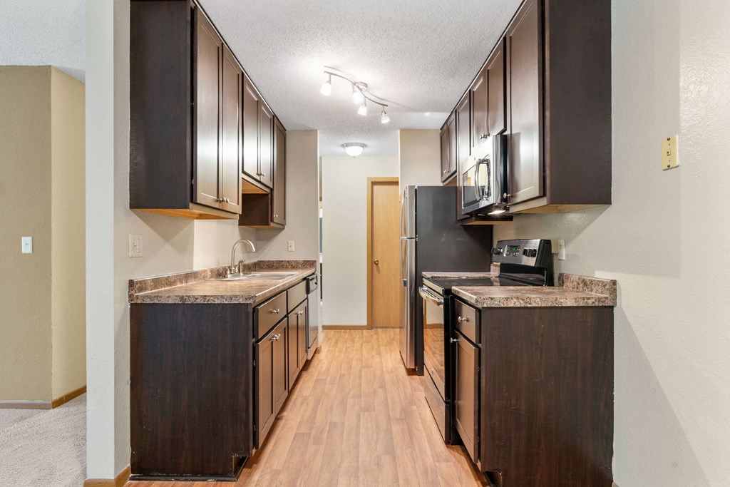 a kitchen with dark cabinets and a stove and a refrigerator