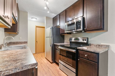 A kitchen with a granite counter top and stainless steel appliances.