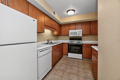 A kitchen with a white refrigerator, brown cabinets, and a white stove top oven.