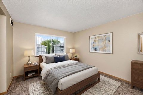 A bedroom with a large bed, two lamps, and a painting on the wall.