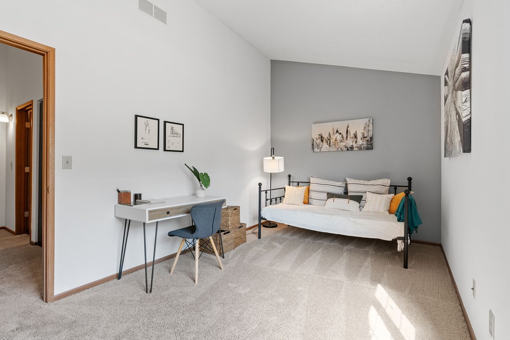 A bedroom with a bed, desk, and chair.