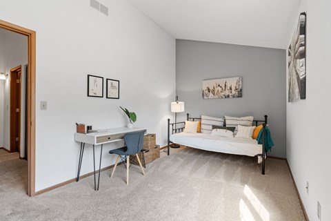 A bedroom with a bed, desk, and chair.