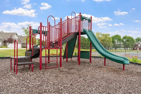 A red and green playground slide in a park.