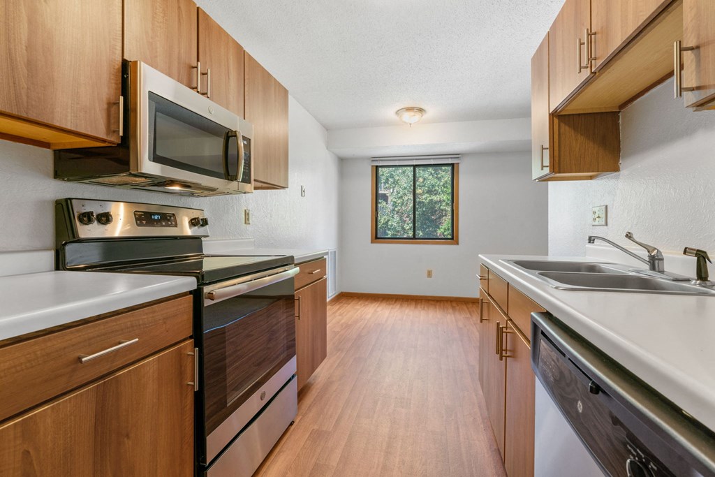 an empty kitchen with wooden cabinets and stainless steel appliances