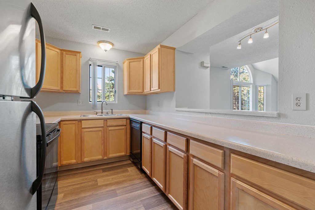 A kitchen with wooden cabinets and a black refrigerator.