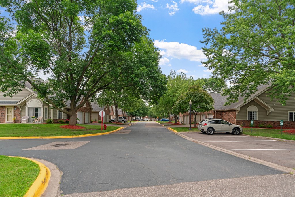 A residential street with houses on both sides and a car parked on the right side.