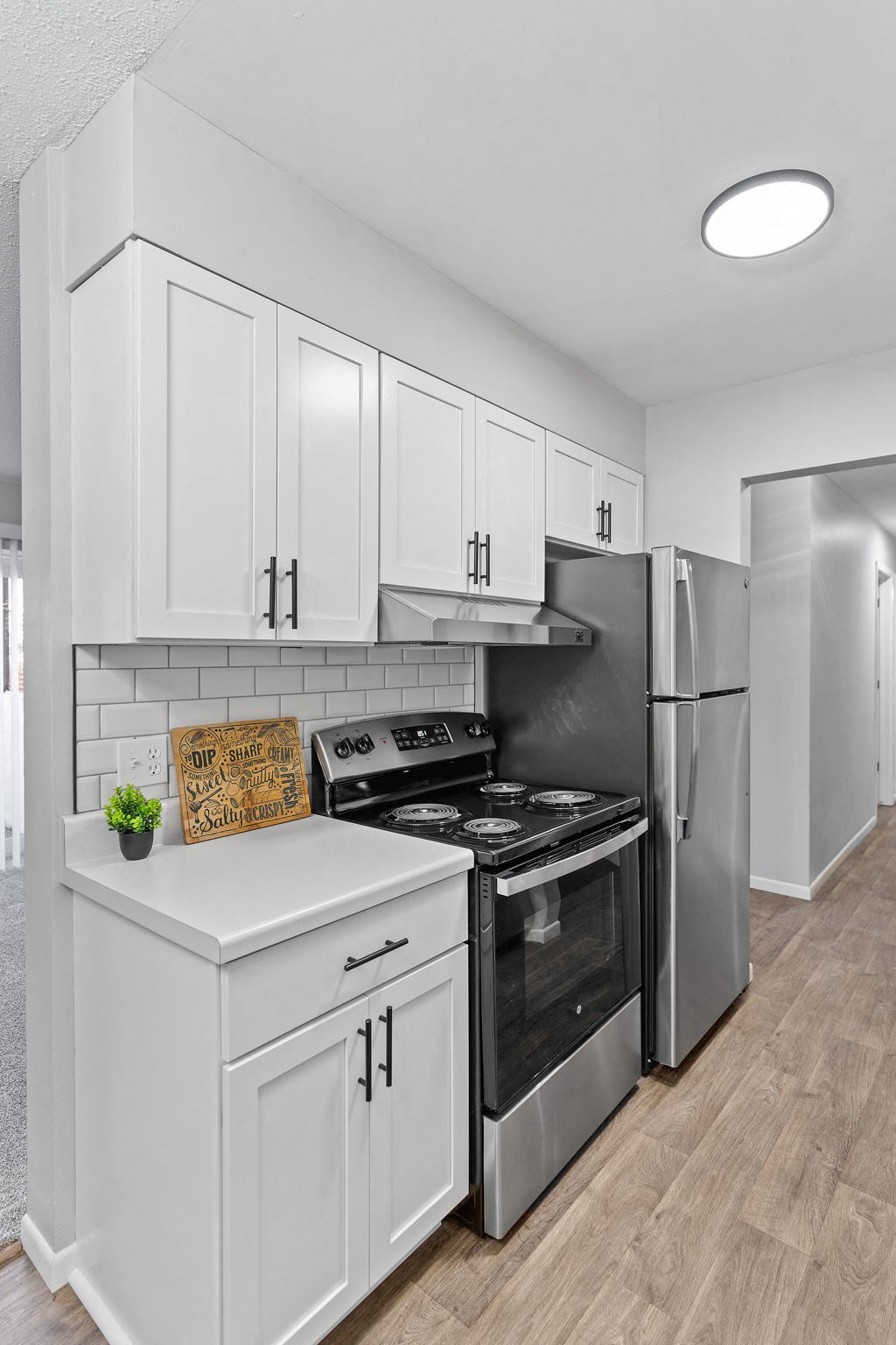 a white kitchen with stainless steel appliances and white cabinets