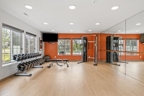 A gym with orange walls and wooden floors.