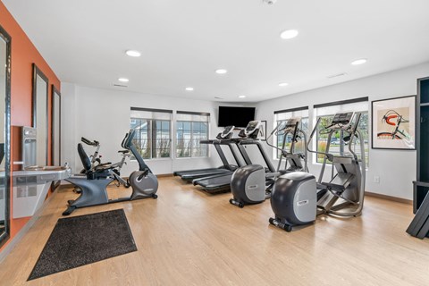 A gym with treadmills, exercise bikes, and a television.