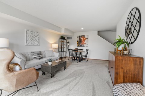 A living room with a grey sofa, a wooden side table, and a large artwork on the wall.