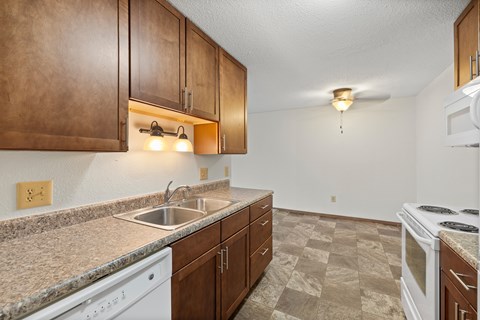 A kitchen with brown cabinets and a white dishwasher.