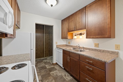 A kitchen with brown cabinets and a white dishwasher.