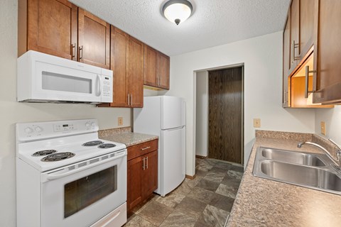 A kitchen with white appliances and wooden cabinets.