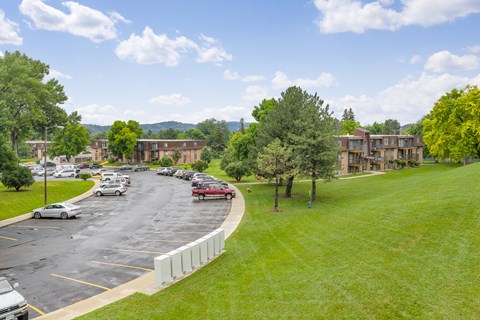 A parking lot with cars and a grassy area in front of a building.