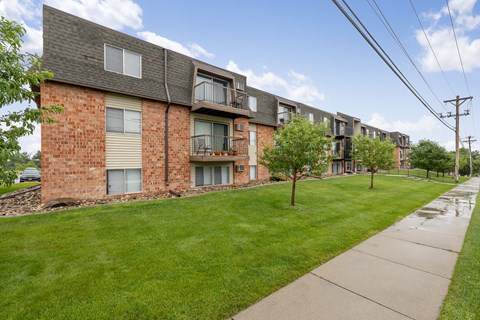 A row of red brick apartment buildings with green lawns in front.