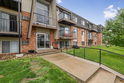 Apartment building with a black railing and a red chair.