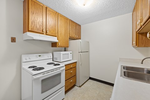 A kitchen with white appliances and wooden cabinets.