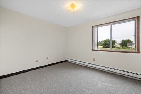 A room with a window and a carpeted floor.