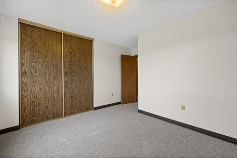 A room with a white wall and a brown door.