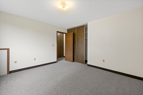 A room with a carpeted floor and two doors.