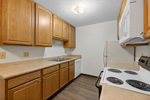 A kitchen with wooden cabinets and a white stove top oven.