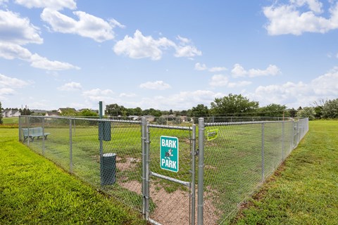 A sign that says "Bark & Park" is attached to a chain link fence.