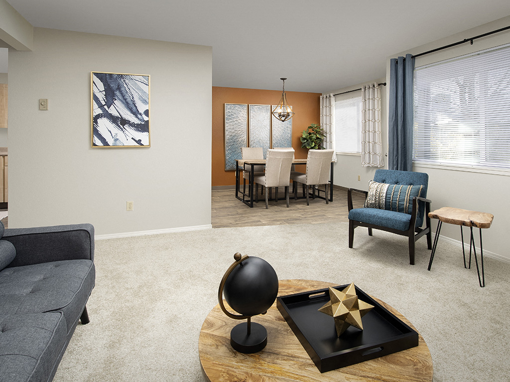 A living room with a grey sofa, a wooden coffee table, and a painting on the wall.