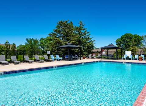 our resort style swimming pool is surrounded by lounge chairs and umbrellas