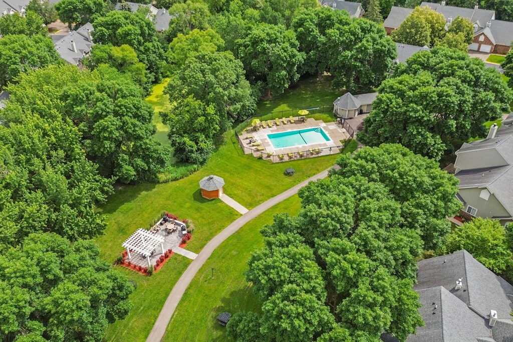 A bird's eye view of a house with a pool surrounded by trees.