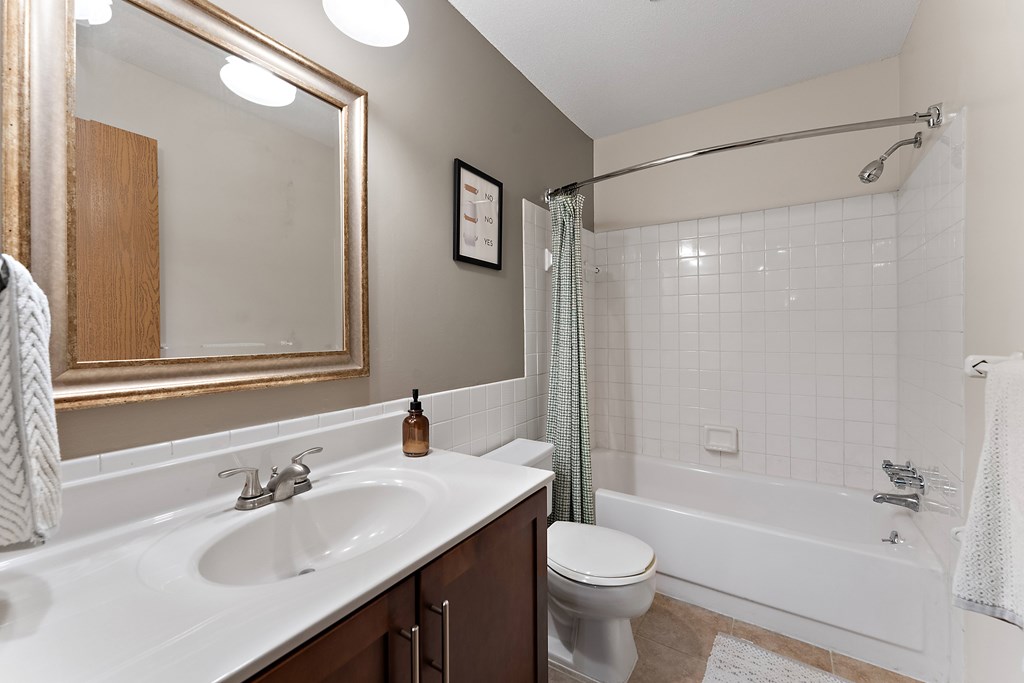 A white sink with a gold faucet and a toilet in a bathroom.