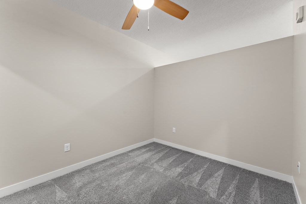 A room with a ceiling fan and a carpeted floor.