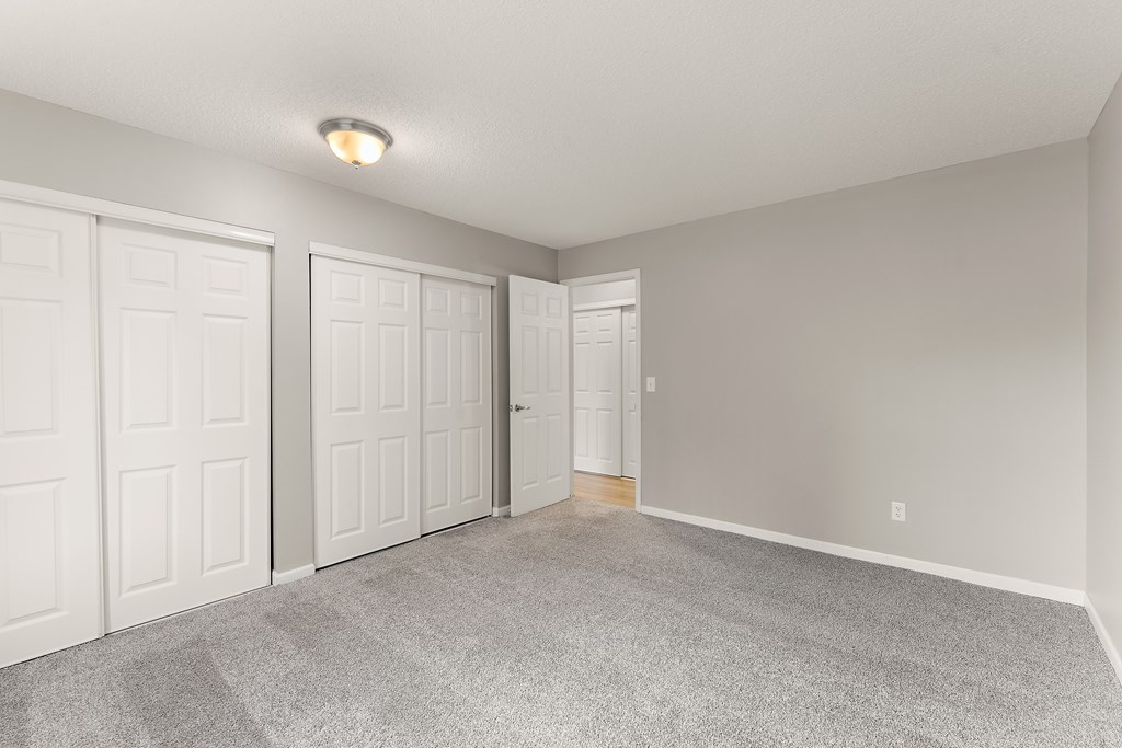 A room with three white doors and a grey carpet.