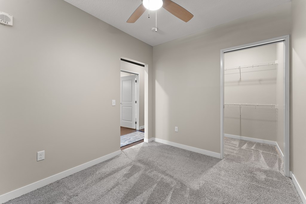 A room with a ceiling fan and a carpeted floor.