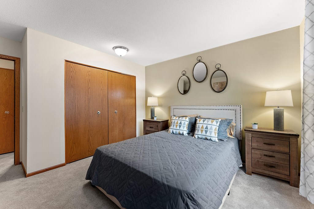 A bedroom with a bed, nightstand, and wardrobe.