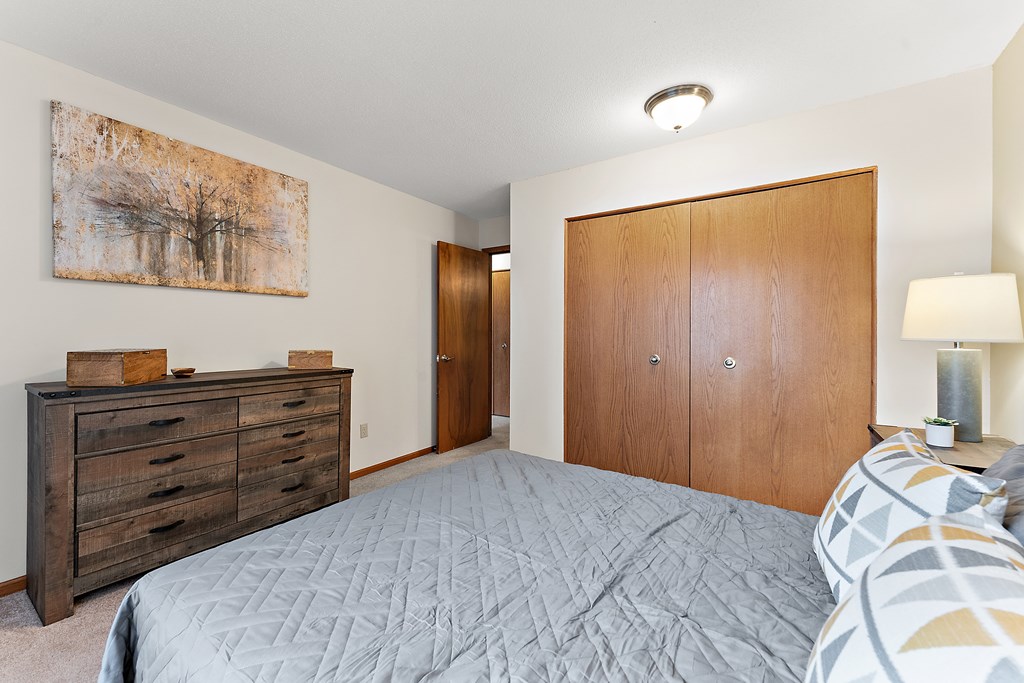 A bedroom with a bed, dresser, and painting on the wall.