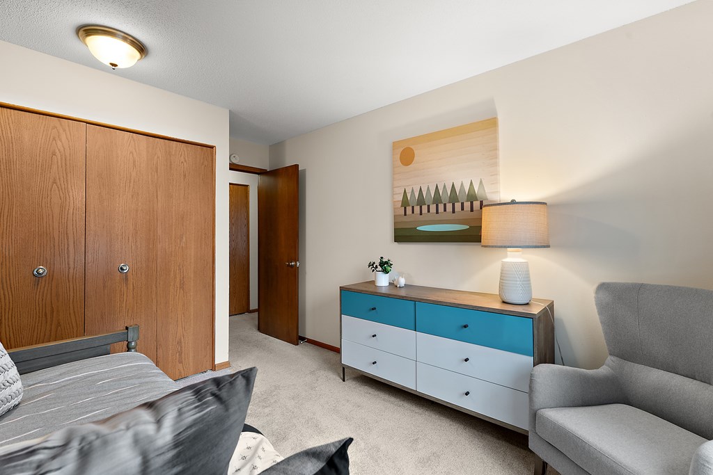 A living room with a grey couch, a wooden cabinet, and a painting on the wall.