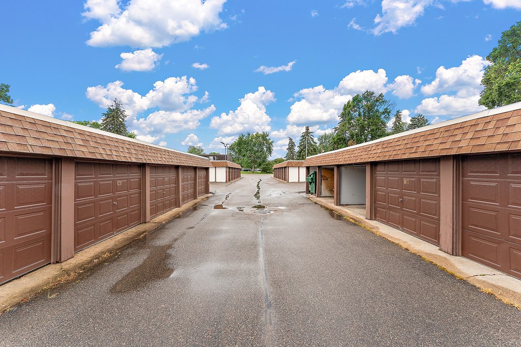 A long, narrow driveway with brown garage doors on either side.