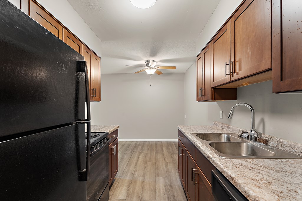 A kitchen with a black refrigerator and wooden cabinets.
