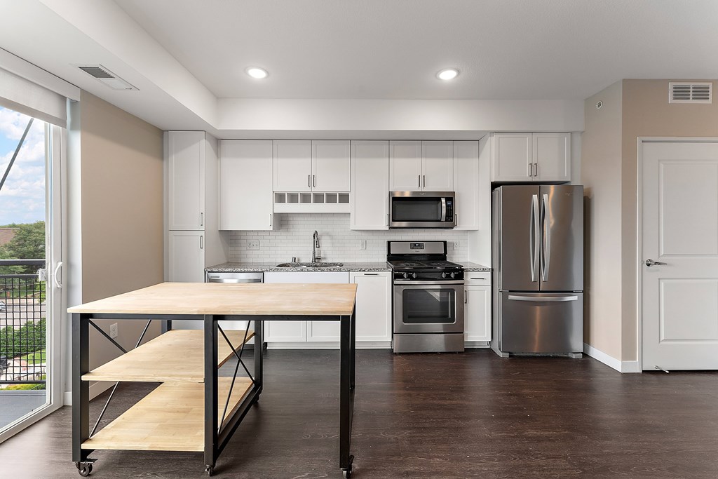 A kitchen with a table and stainless steel appliances.