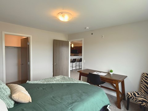 A bedroom with a bed, desk, and chair.
