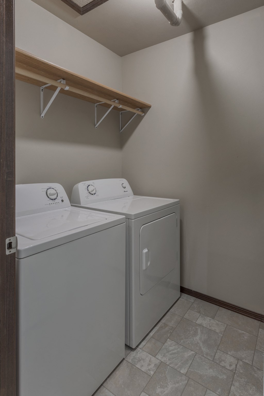 a white washer and dryer in a laundry room with a shelf above it