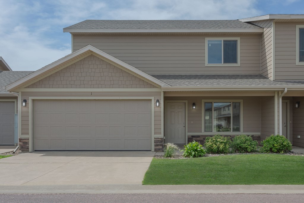 A house with a grey garage door and a brown roof.