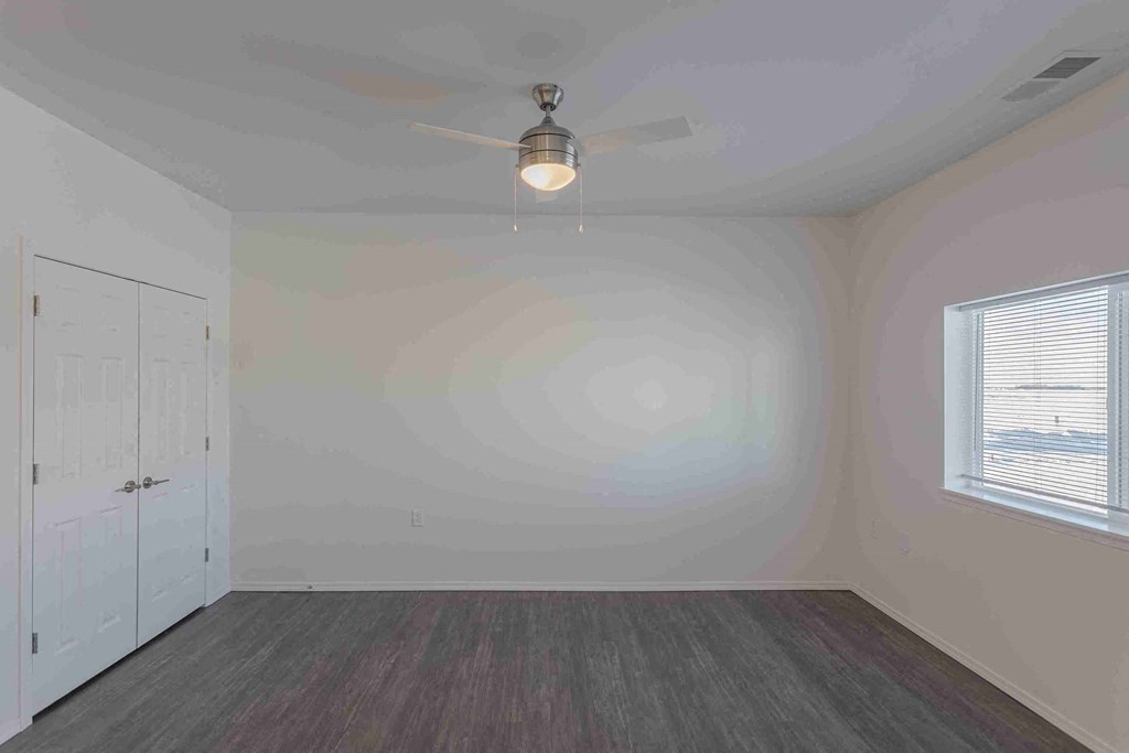 an empty bedroom with a ceiling fan and a closet
