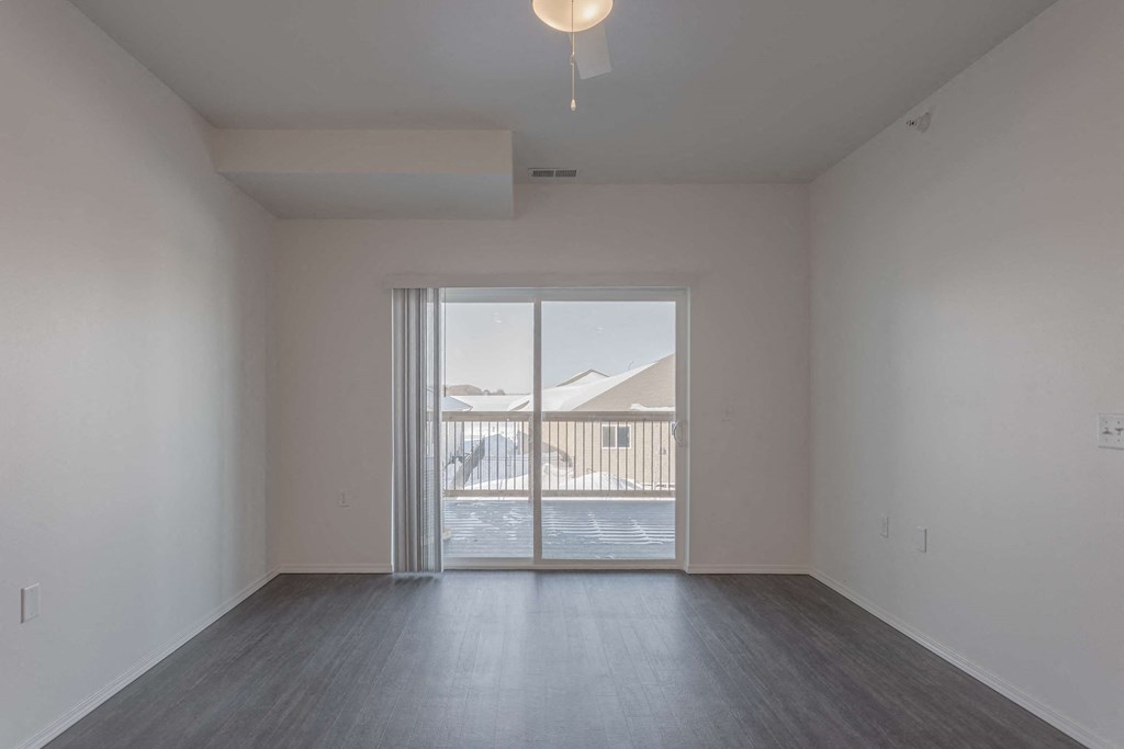 an empty living room with a sliding glass door to a patio