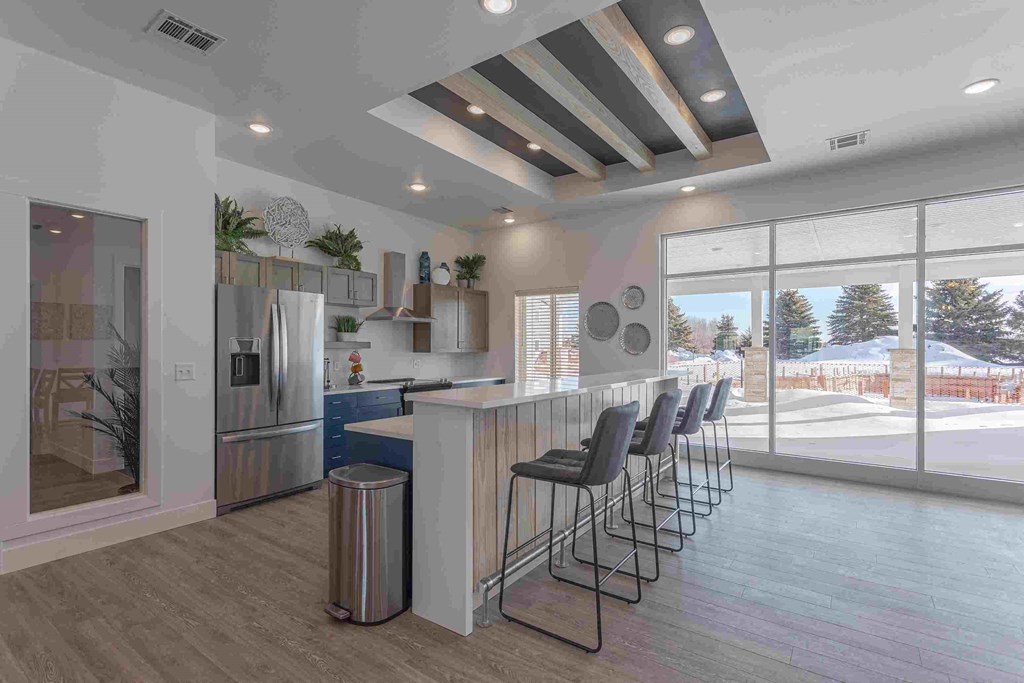 a kitchen with a bar and chairs in front of a window