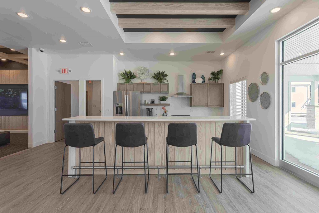 a kitchen with a counter and three chairs