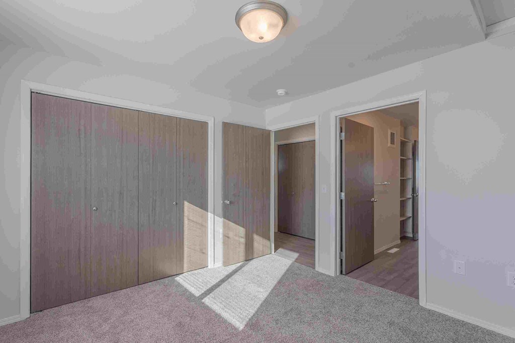 an empty room with a carpet and a door to a closet