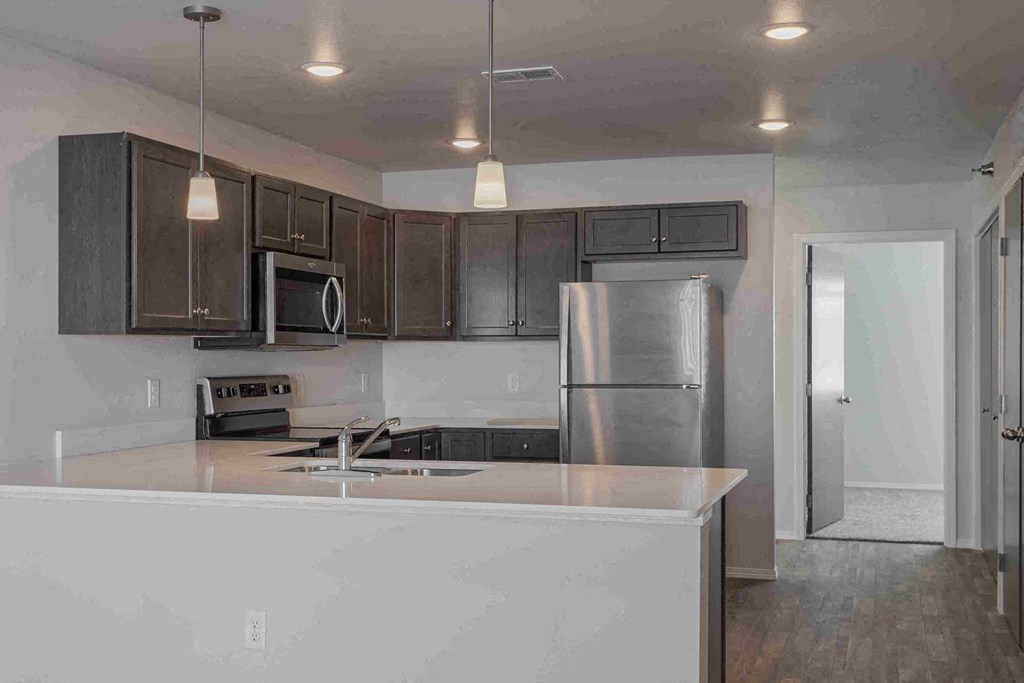 a kitchen with a white counter top and a stainless steel refrigerator