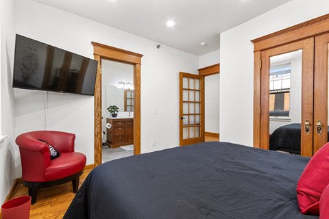 A bedroom with a large bed and a red chair.