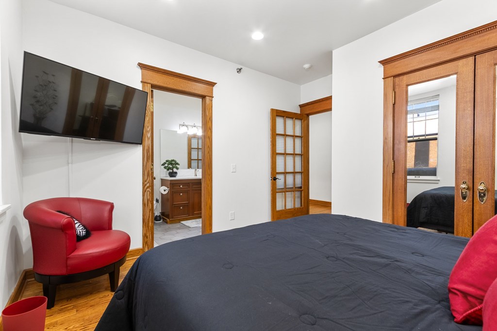 A bedroom with a large bed and a red chair.